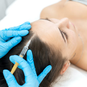 Close-up, the beautician makes injections of vitamins into the scalp for strengthening the hair
